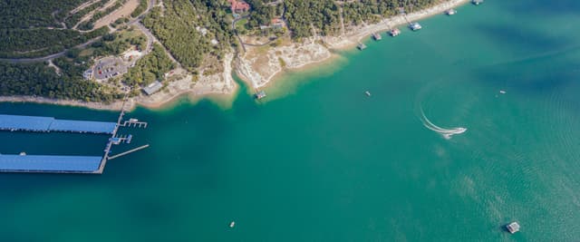 Aerial view of Lake Travis with emerald water, boat docks, and cedar-covered hills